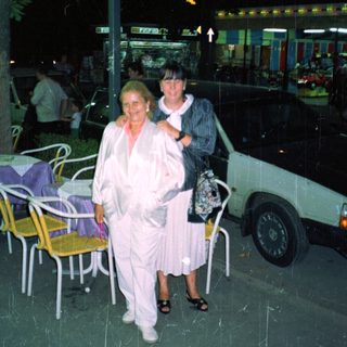 Two women stand outside a store at night.