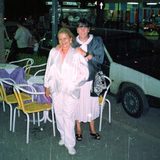 Two women stand outside a store at night.