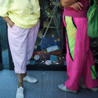 Two women stand outside a store in vibrant, sporty clothing.