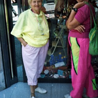 Two women stand outside a store in vibrant, sporty clothing.