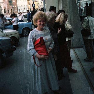 People stand near a storefront with a town scene visible.