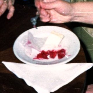 Two women sit at a table, eating cake.