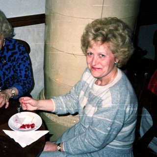 Two women sit at a table, eating cake.