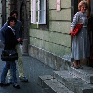 People stand near a building with a storefront and sign.