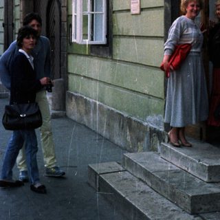 People stand near a building with a storefront and sign.