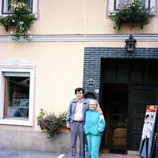 Couple poses outside a building with floral details.