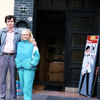 Couple poses outside a building with floral details.