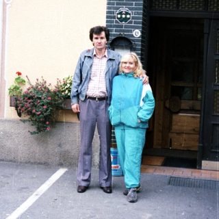 Couple poses outside a building with floral details.