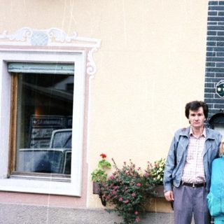 Couple poses outside a building with floral details.