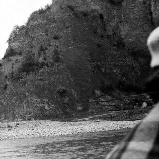 Rocky hillside overlooking a riverbed with a person visible.