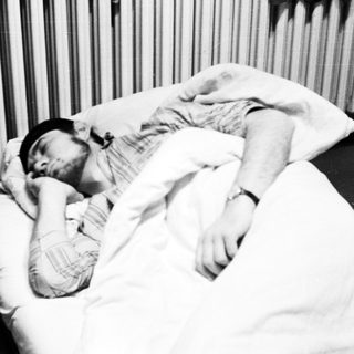 Man sleeping in bed with a black hat.