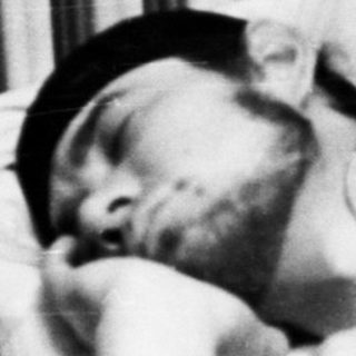Man sleeping in bed with a black hat.
