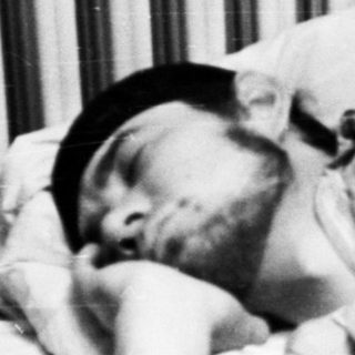 Man sleeping in bed with a black hat.
