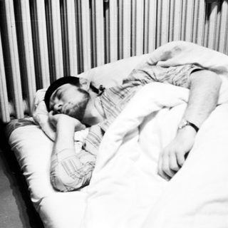 Man sleeping in bed with a black hat.