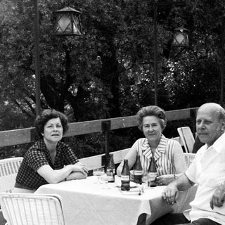 Three people seated at a table outdoors.