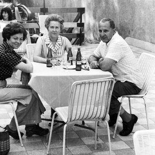 Group of three people seated at a table outdoors.