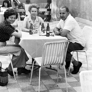Group of three people seated at a table outdoors.