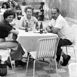 Group of three people seated at a table outdoors.