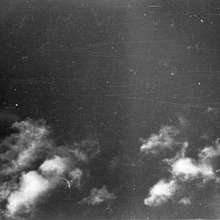 Dark sky with scattered clouds and visible scratches.