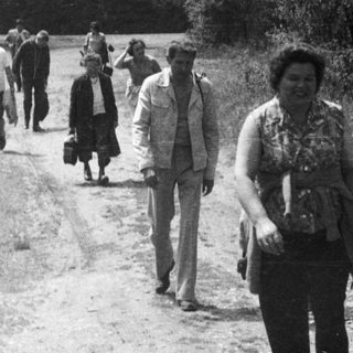 Group of people walk along a rural, unpaved road.