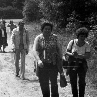 Group of people walk along a rural, unpaved road.