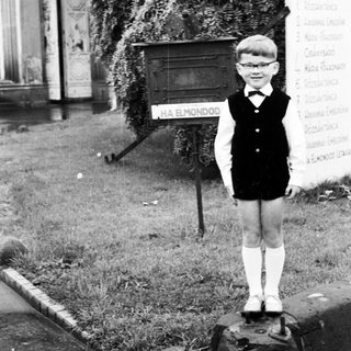 Boy in vintage clothing stands on a stone pedestal.