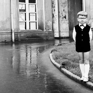 Boy stands near building in a flooded street.