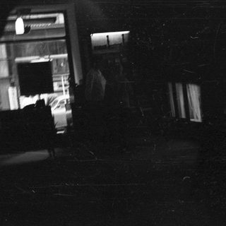 Dark, grainy view of a building with a car inside.