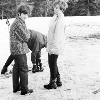 Here's a brief summary of the image: Two people in snowy landscape; one appears to be struggling.
