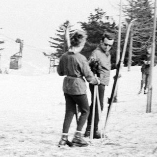 People skiing near a vintage ski lift in winter.
