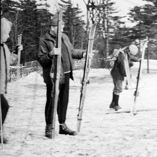 People skiing near a vintage ski lift in winter.
