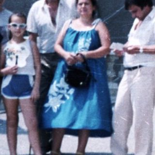 Family stands near a stone building with a bust.