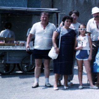 Family stands near a stone building with a bust.