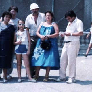 Family stands near a stone building with a bust.