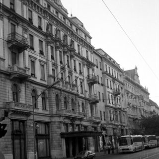 Elegant buildings line a street with tram tracks and traffic.