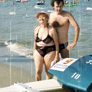 People on a beach next to a racing hydroplane boat.
