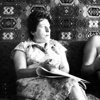 Black and white photo of two people seated on a sofa.