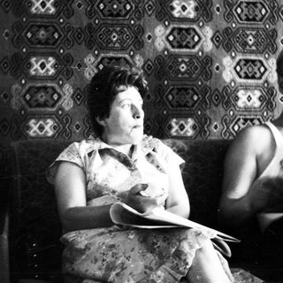 Black and white photo of two people seated on a sofa.