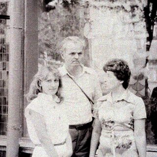 Man stands between two girls in front of a building.