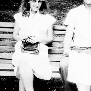 Three people sit on a park bench in black and white.