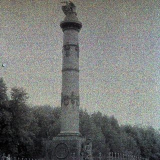 Monument with a statue atop, surrounded by a fence.