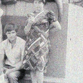 Three people pose near a stone lion statue.