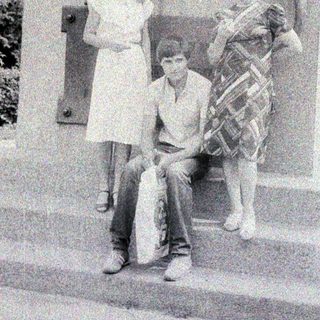 Three people pose near a stone lion statue.