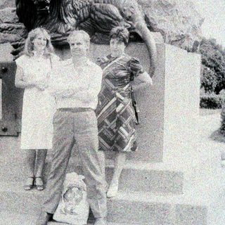 People pose near a statue featuring a lion.