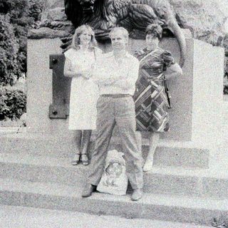 People pose near a statue featuring a lion.
