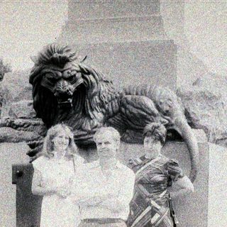 People pose near a statue featuring a lion.