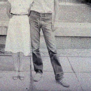 Here's a brief summary of the image: Couple posing outdoors in front of a building.