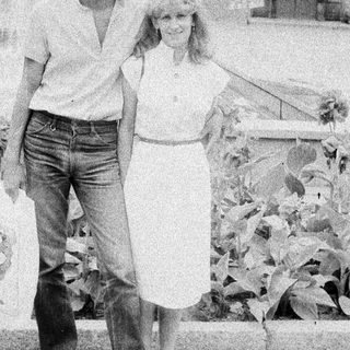 Here's a brief summary of the image: Couple walking outdoors, appearing relaxed and casual.