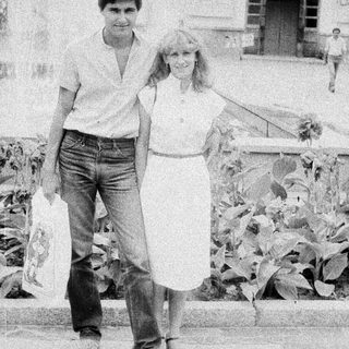 Here's a brief summary of the image: Couple walking outdoors, appearing relaxed and casual.