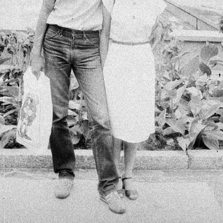 Here's a brief summary of the image: Couple walking outdoors, appearing relaxed and casual.